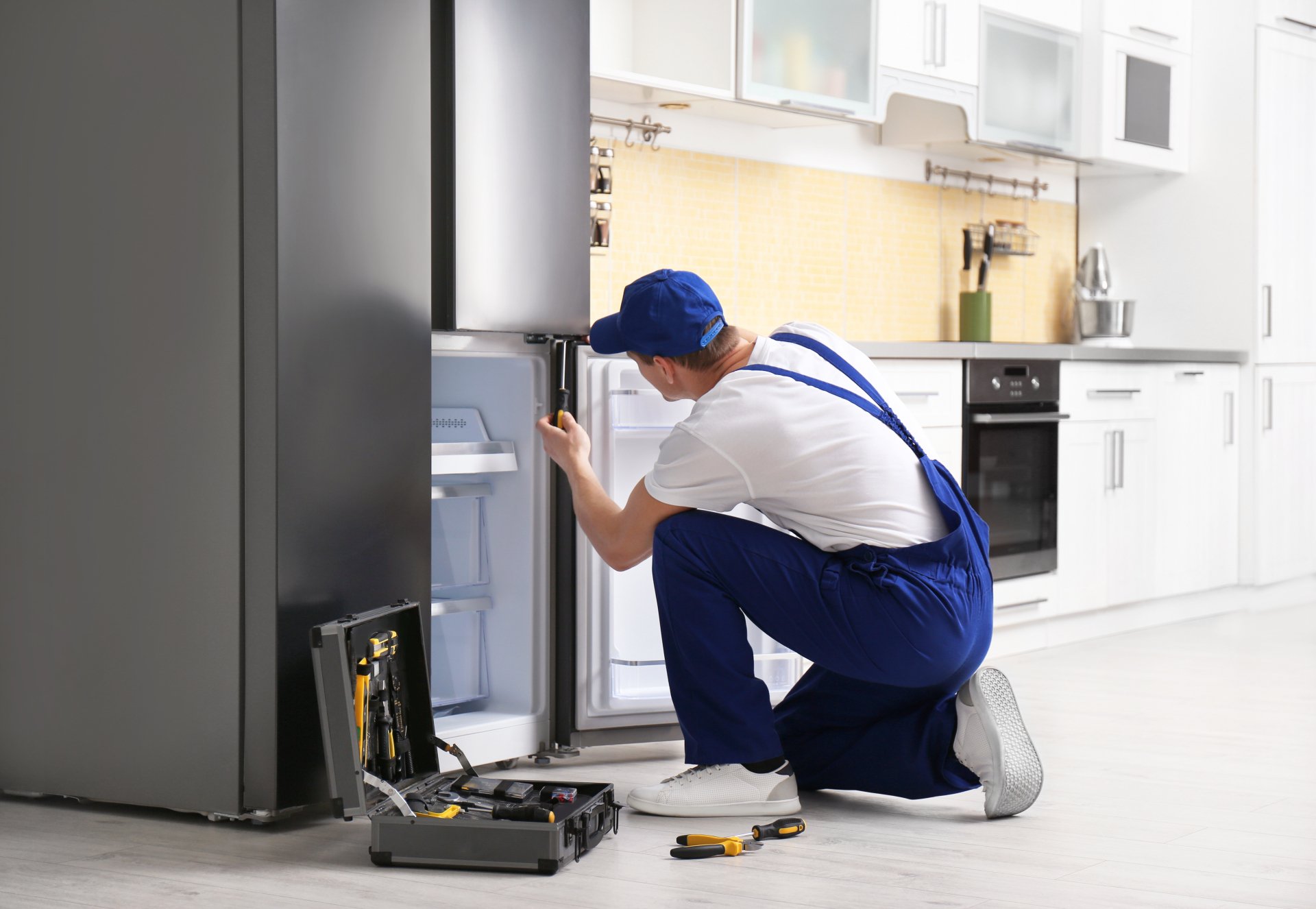 a technician repairing a refrigerator - Best Appliance Repair Atlanta