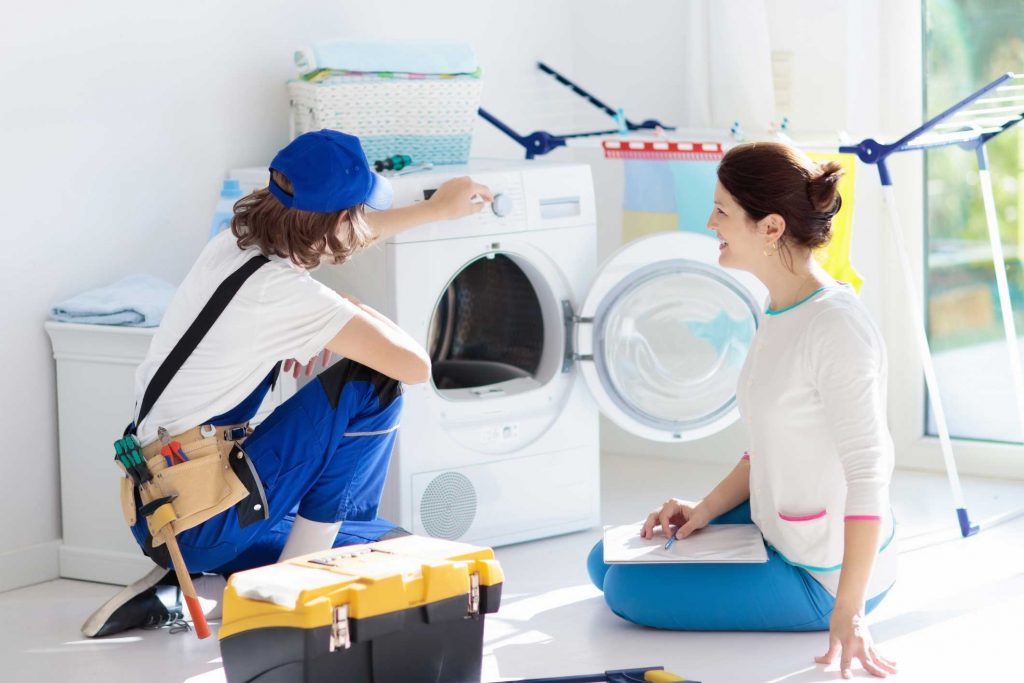 a technician repairing a washer while woman is watching - appliance repair service Atlanta