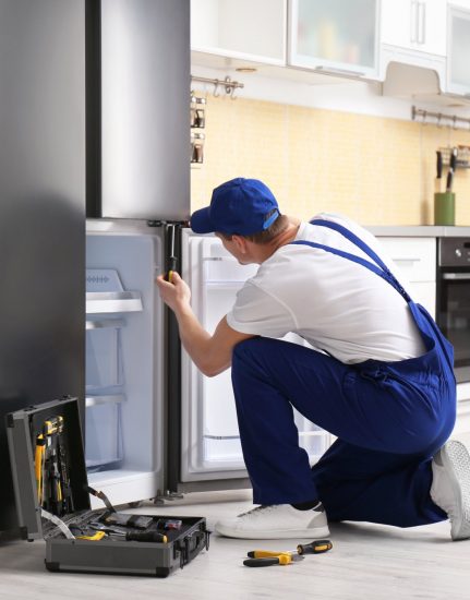 a technician repairing a refrigerator - Best Appliance Repair Atlanta